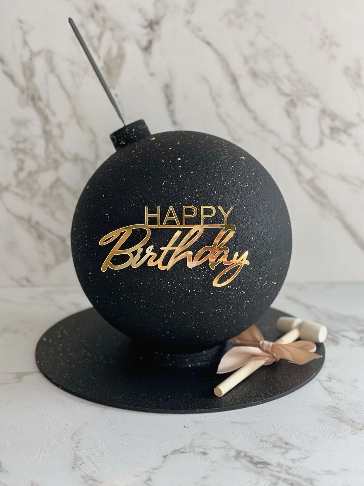 Чёрный шарообразный торт-бомба с золотой надписью Happy Birthday